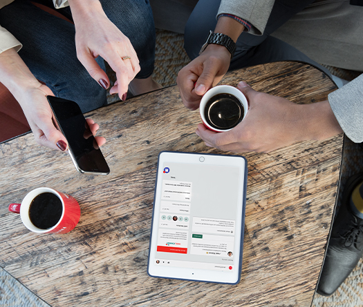 A group of people sitting at a table with coffee and a tablet