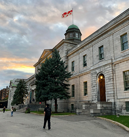 Several students walking in front of the Arts building at dusk
