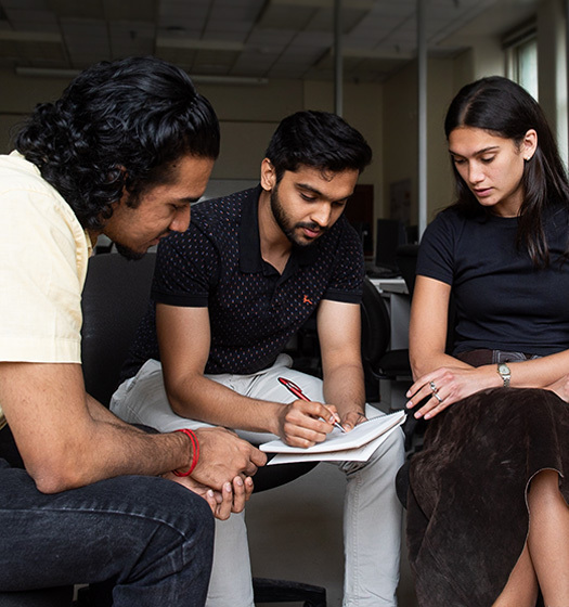A group of people sitting and writing on a book