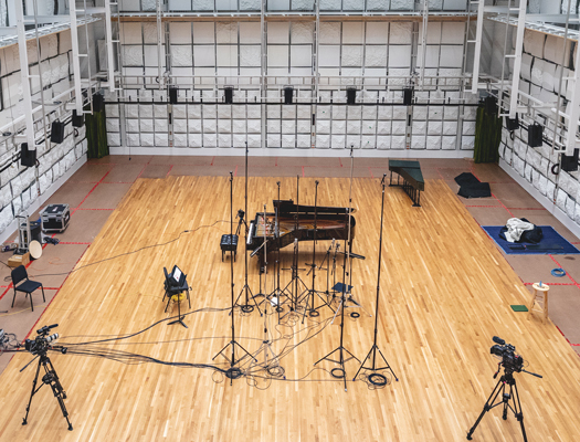 A large empty room with a piano and equipment