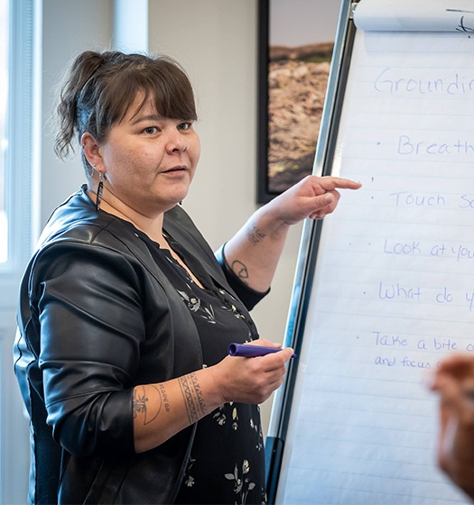 A person standing next to a flip chart, pointing at handwritten notes.
