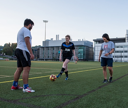 Three people playing on a soccer field.